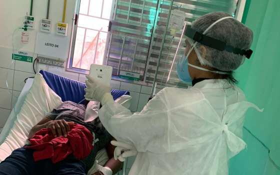 A interação é feita por um profissional de saúde com o paciente no leito hospitalar.